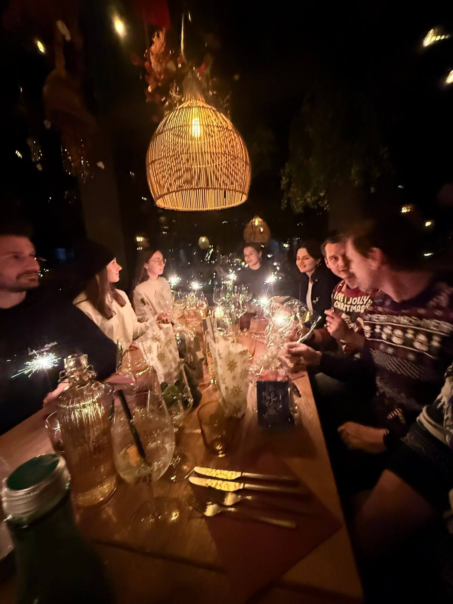 Lange Tafel auf der Dachterrasse, das Team mit Wunderkerzen und Geschenken vor der nächtlichen Stadtkulisse.