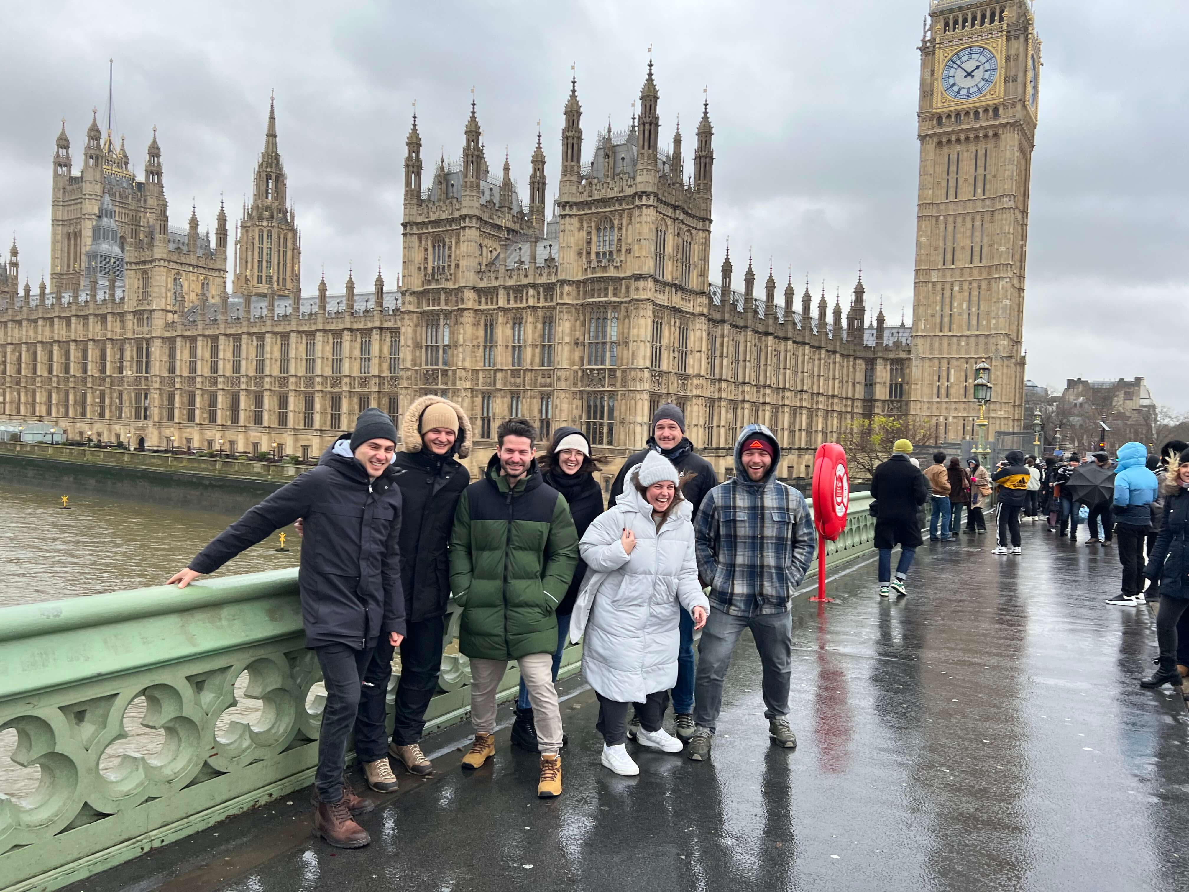 Gruppe von Menschen auf einer Brücke vor dem Big Ben, London, an einem bewölkten Tag.